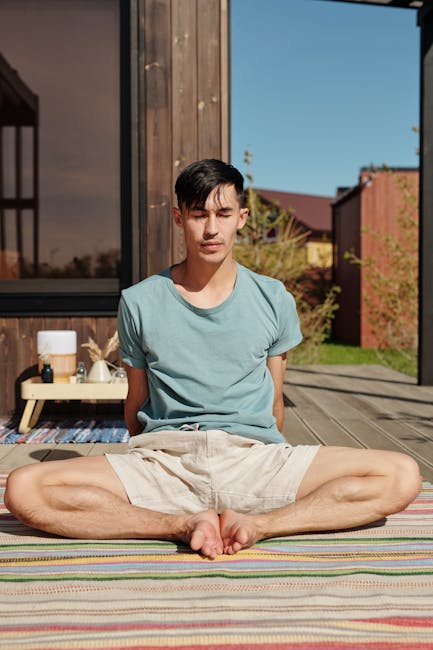 A man sits meditating calmly on a wooden floor.